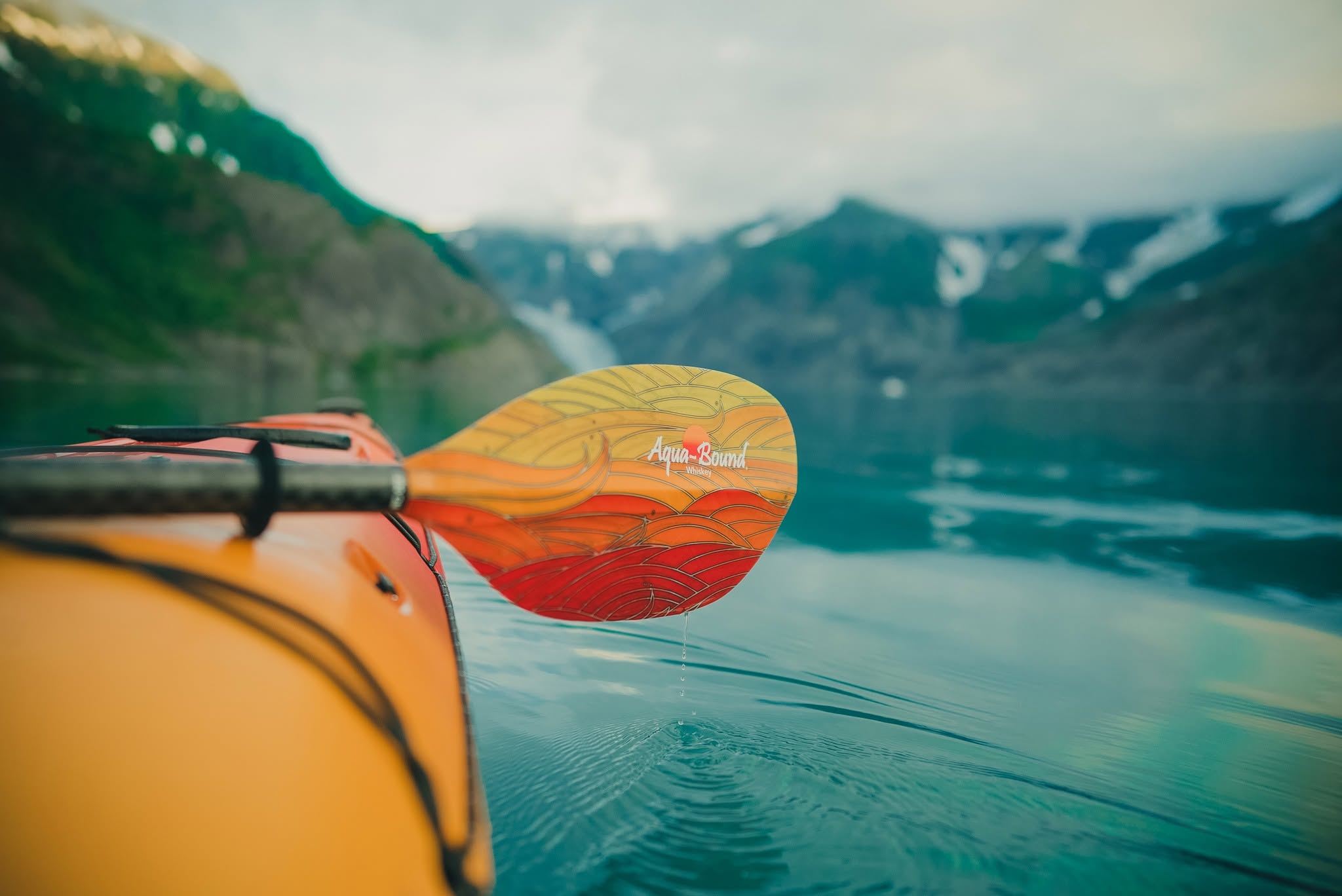 Kayaker paddling a Player 525 sea kayak on a fjord