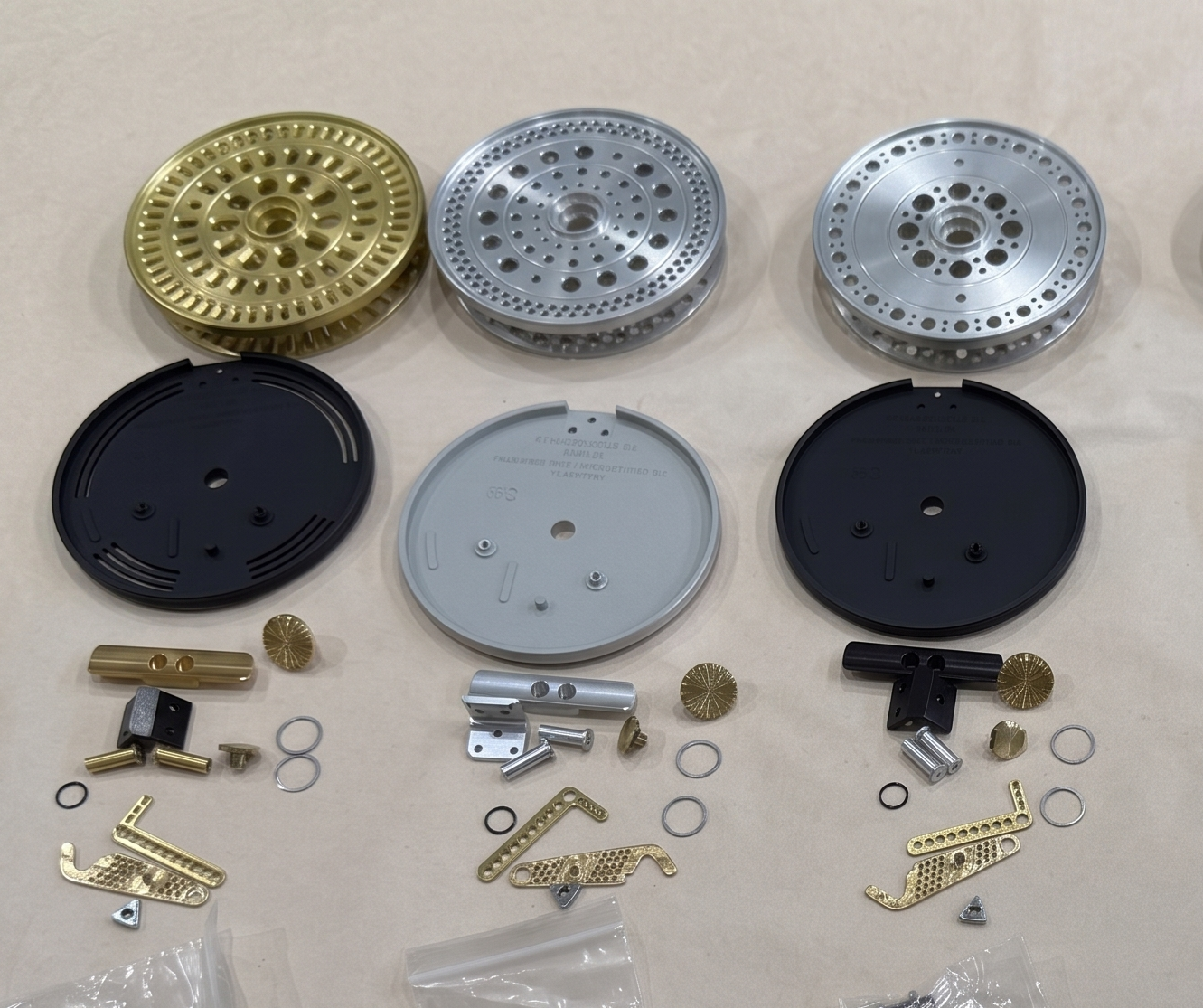 Machined fly reel components — spools, frames, handles, and hardware — laid out before assembly.
