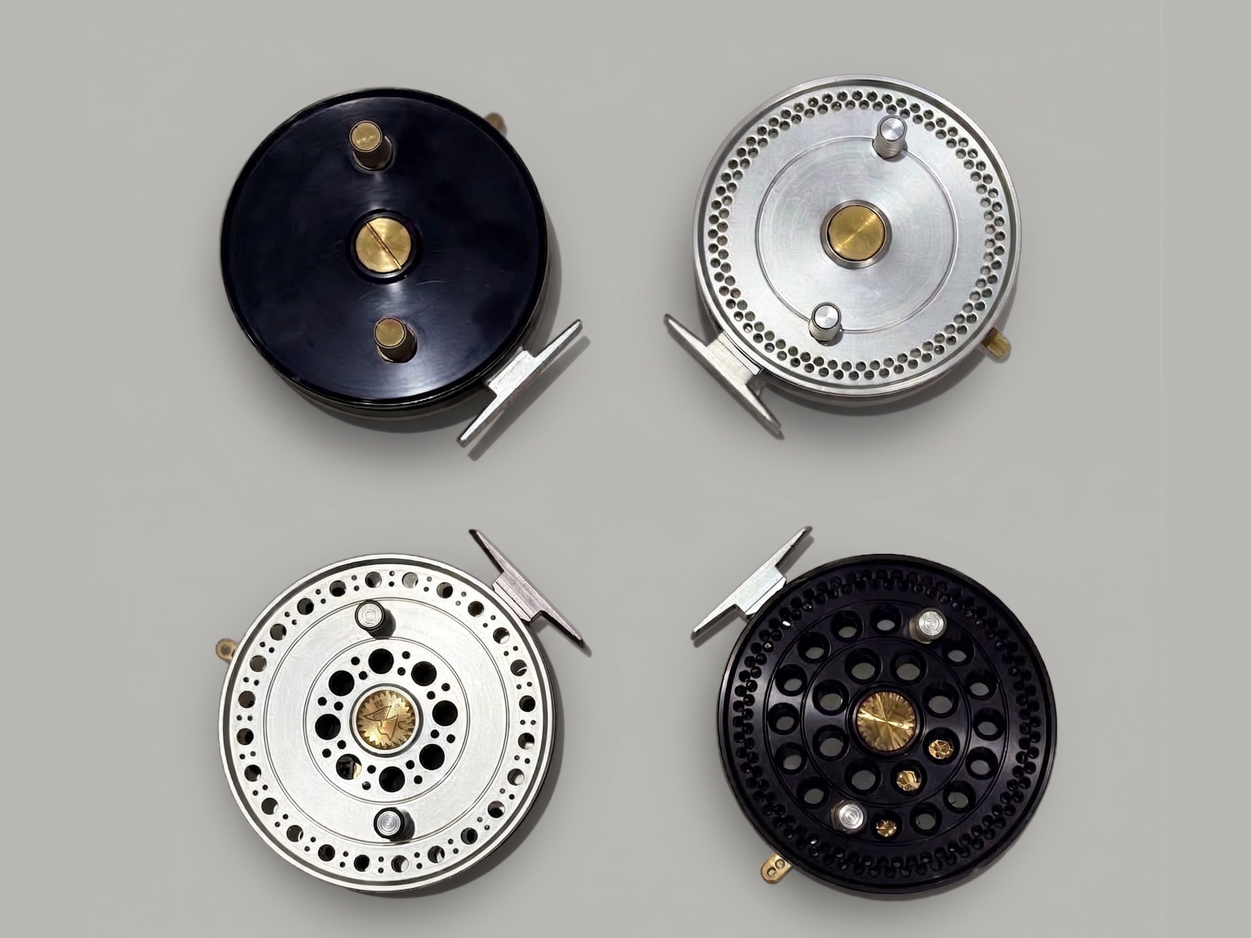 Four assembled fly reels from a low-volume production run in black and silver finishes.