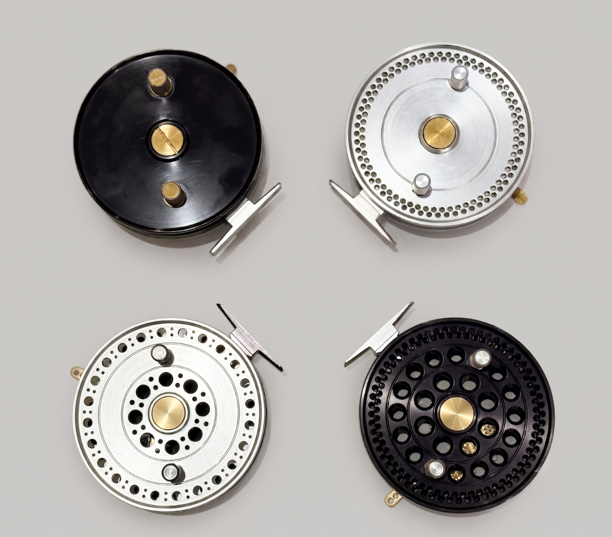 Four assembled fly reels from a low-volume production run in black and silver finishes.