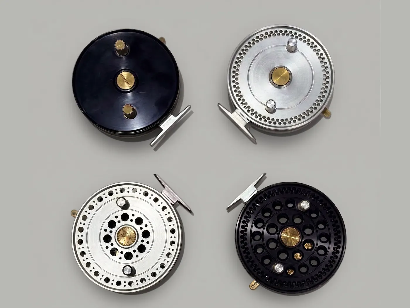 Four assembled fly reels from a low-volume production run in black and silver finishes.