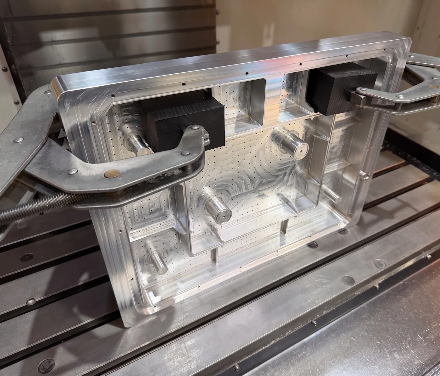 A large aluminum frame held with toe clamps and being machined on a CNC mill.