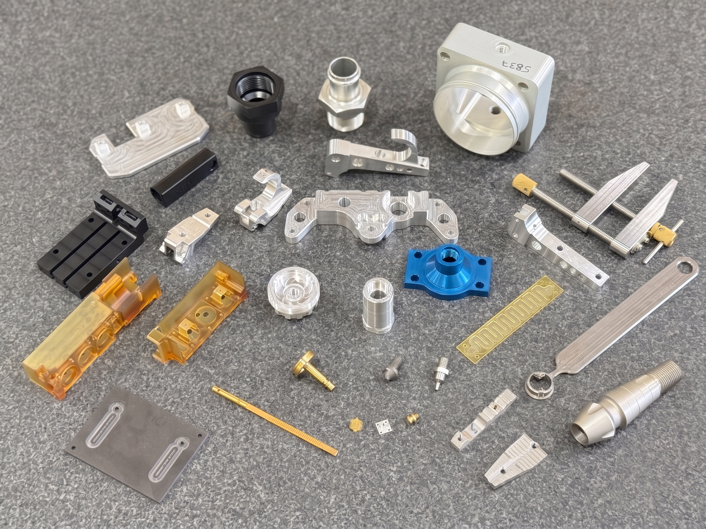 An assortment of precision-machined components in aluminium, steel, brass, and coloured anodised finishes.