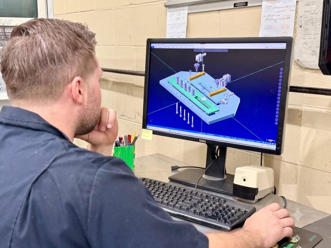 An engineer reviewing a 3D CAD model of a machining fixture on-screen during design.