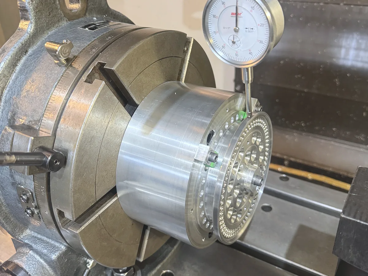 Dial indicator checking runout on a part held in a lathe chuck