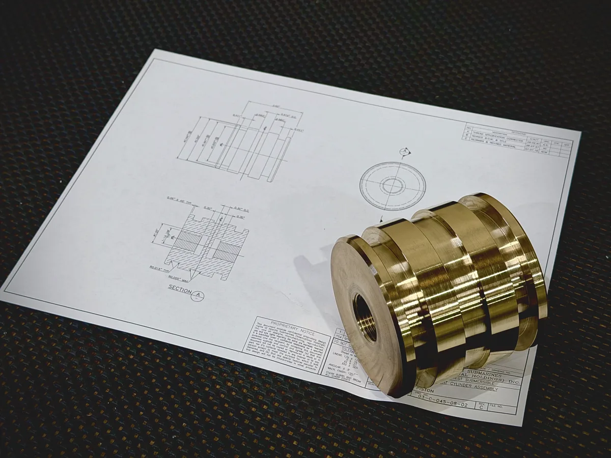 Brass grooved cylinder resting on the engineering drawing it was made from