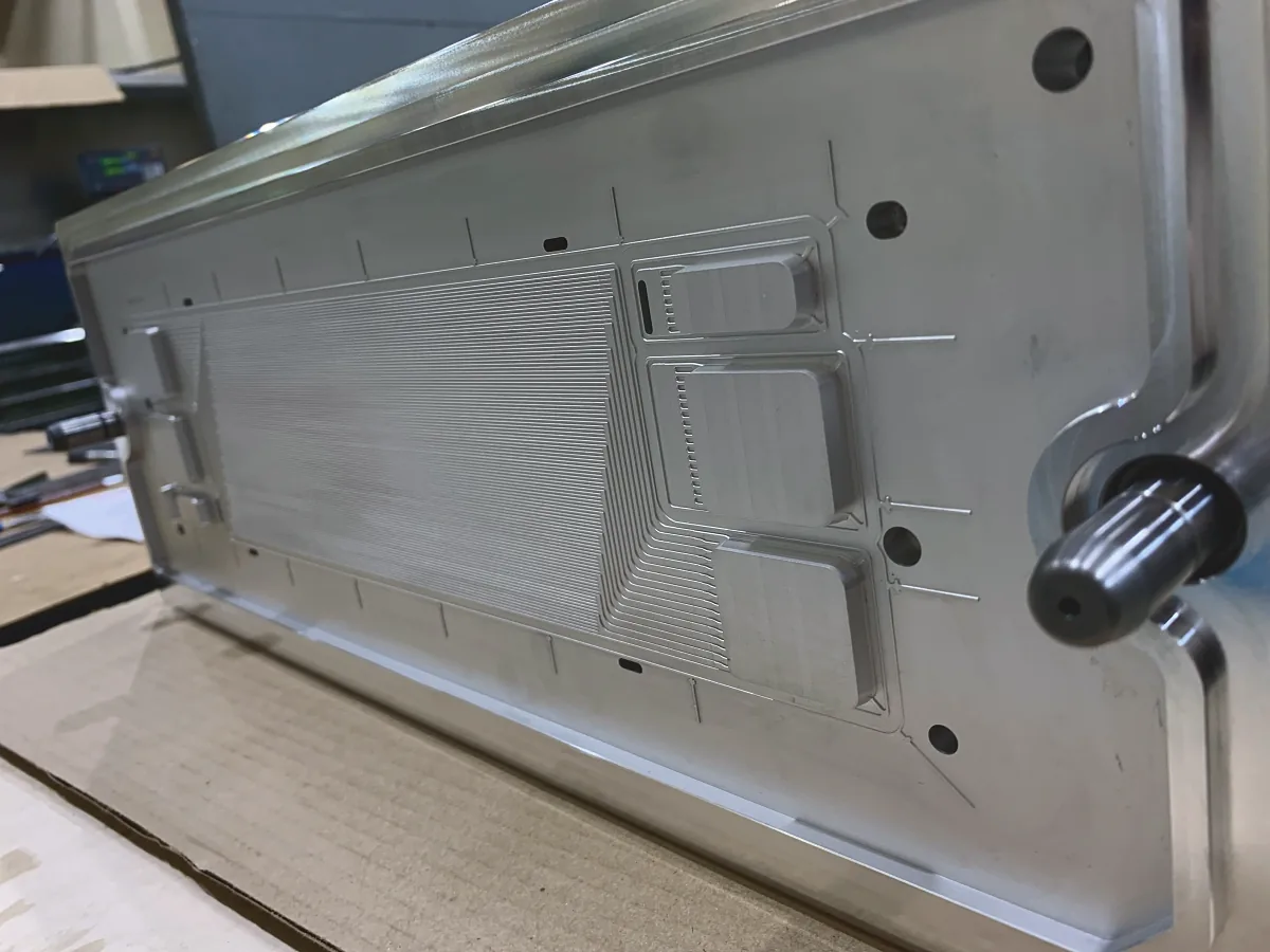Long aluminum plate with fine parallel grooves and machined pockets