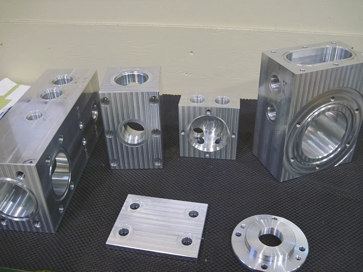 Aluminum manifold blocks with bored and threaded ports, a cover plate and a flange