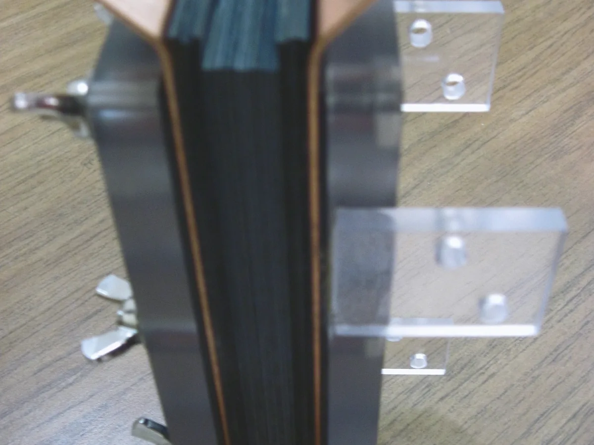 Stacked dark plates held in a fixture with acrylic guides